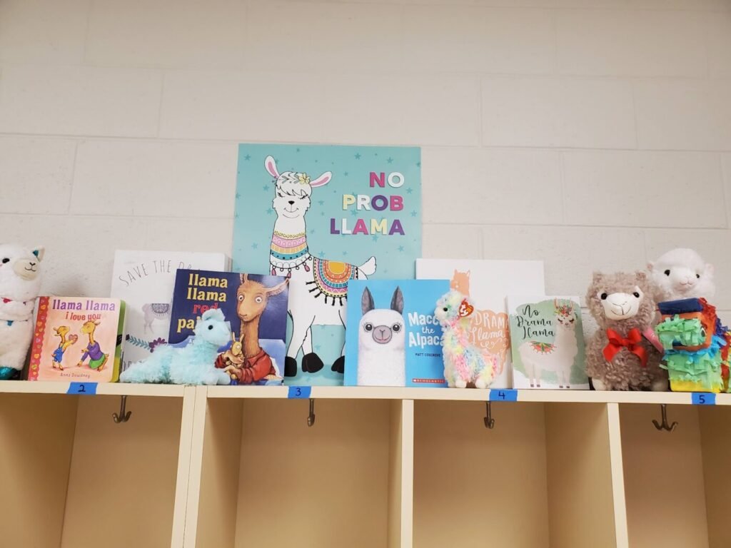 Shelf display of stuffed llamas and picture books in a classroom corner