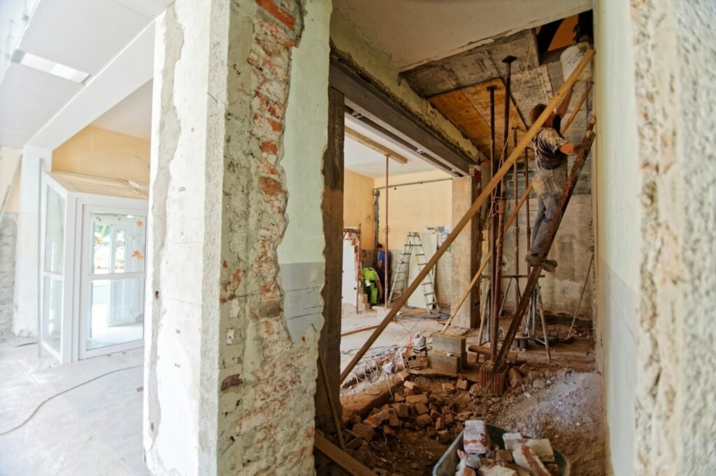 Interior home renovation in progress with contractors removing walls and installing structural supports, representing remodeling and construction services in North Atlanta.