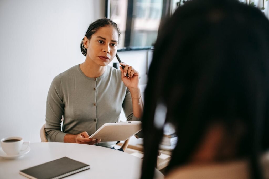 Illustration of a therapist speaking with a client during a counseling session in a private office setting.