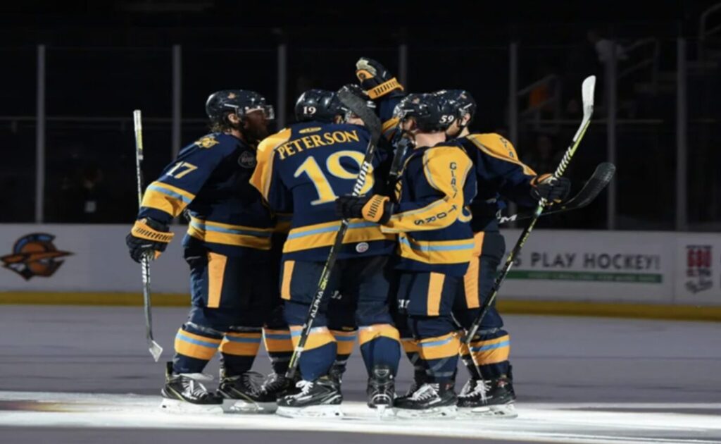 Photo of Atlanta Gladiators players huddle on the ice in Duluth before a home hockey game.