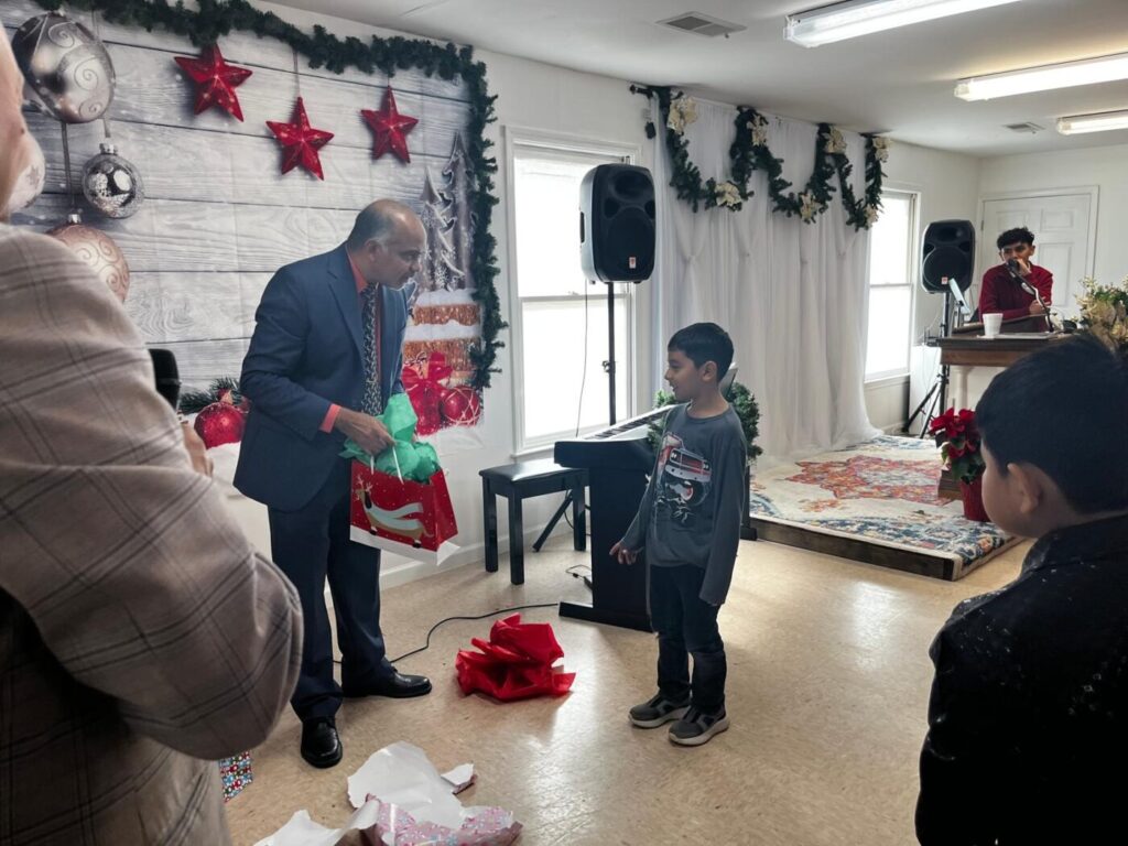 Mathew Philip speaks with a child during a community holiday event in Forsyth County, reflecting his local engagement as he announces his campaign for Georgia State House District 25.