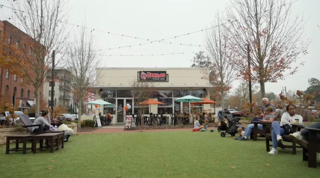 Families relaxing on a lawn outside restaurants in downtown Woodstock, Georgia
