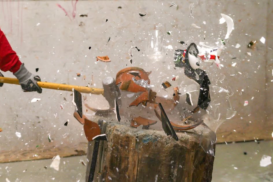 A bat strikes a glass object, sending shards flying across a smash room.