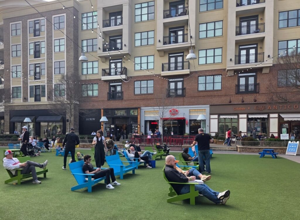 Visitors relaxing on the central lawn at Avalon in Alpharetta surrounded by restaurants and shops