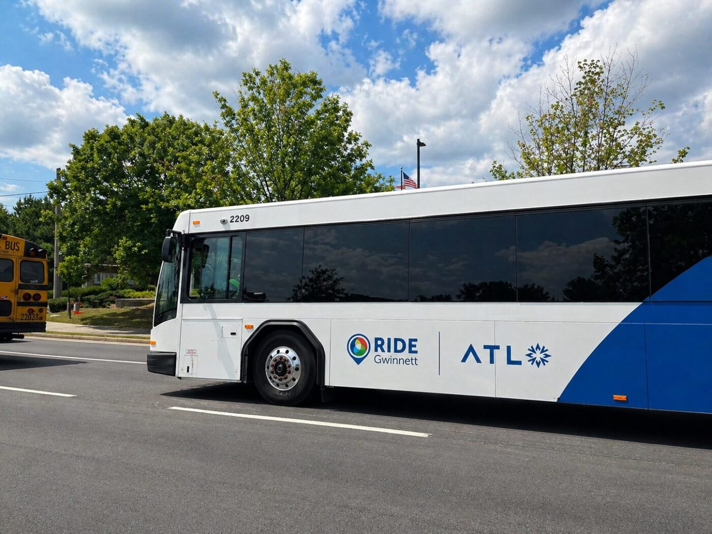 White transit bus with Ride Gwinnett and ATL logos on the side, parked on a road under a cloudy sky.
