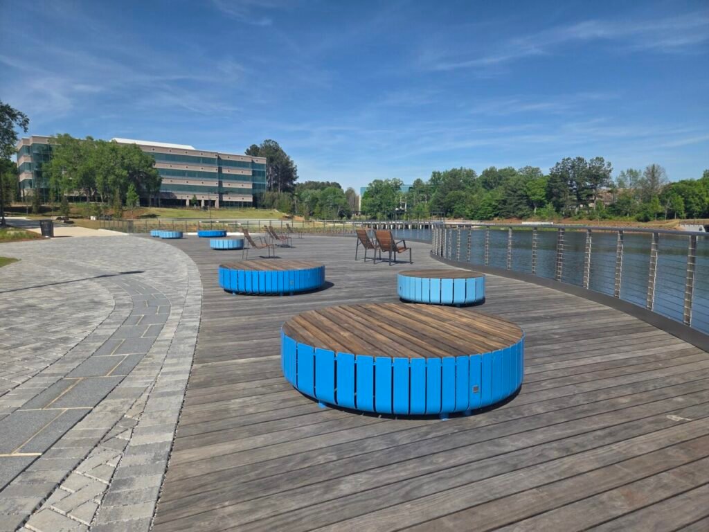 Wooden deck with blue circular seating beside the water and office buildings in the background