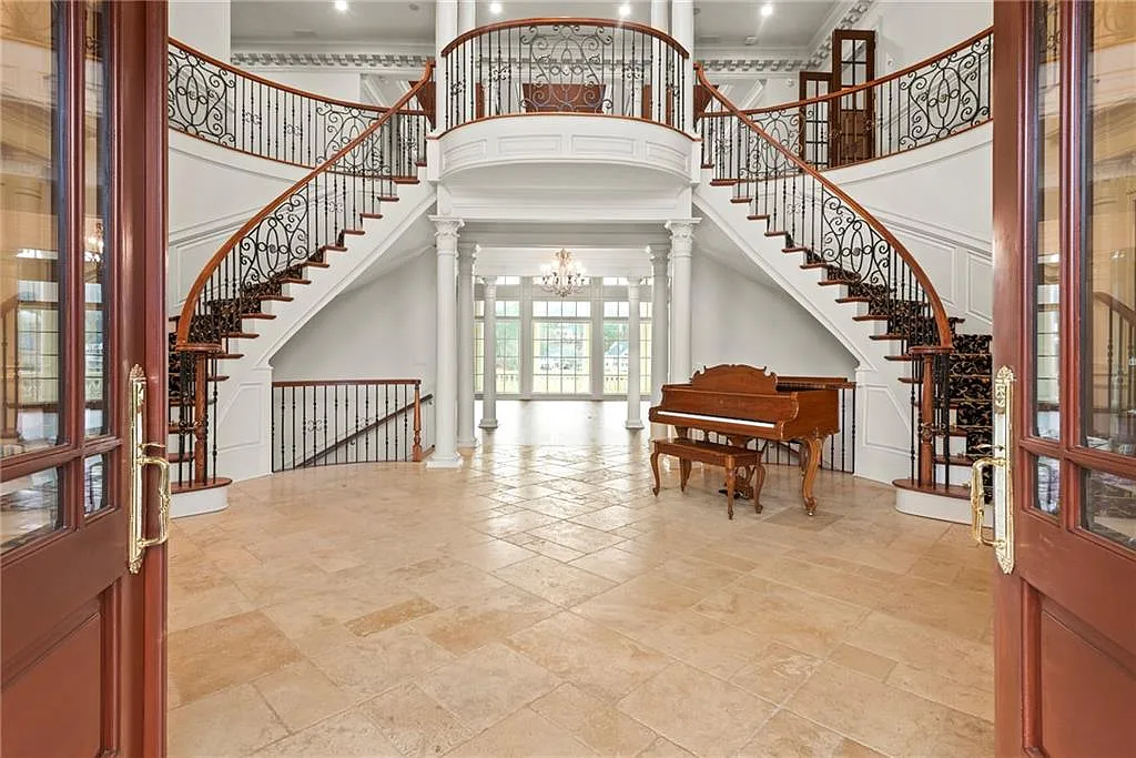 A dramatic two-story foyer with dual sweeping staircases framing the space.