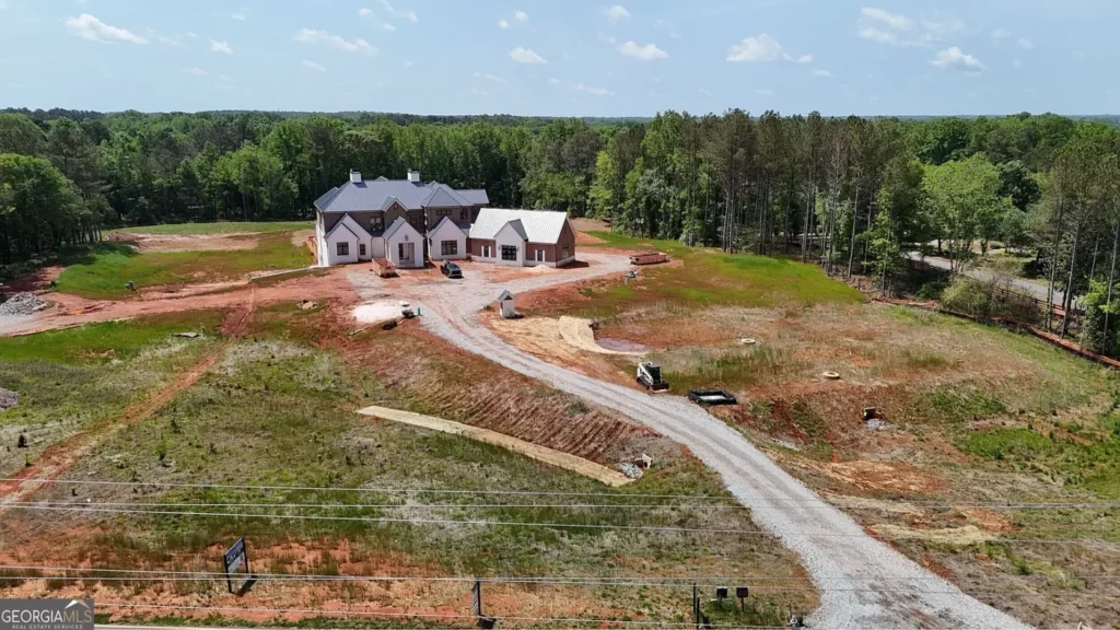 Aerial view of a large unfinished luxury estate on a 12-acre property in Milton, Georgia, surrounded by trees and open land.
