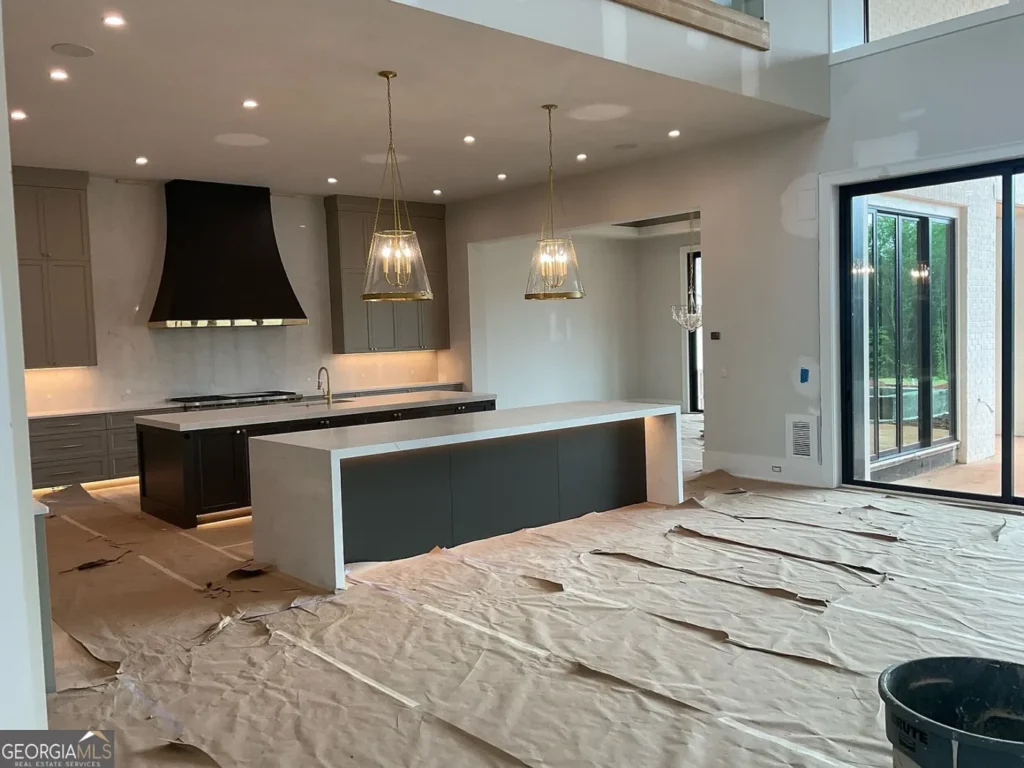 Interior view of an unfinished luxury kitchen in a Milton, Georgia estate, with double islands, pendant lights, covered floors and large windows overlooking the property.
