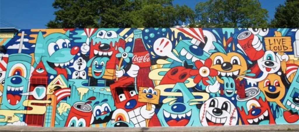 Large outdoor mural by Atlanta artist Greg Mike featuring colorful cartoon-style characters, flowers and pop-art imagery