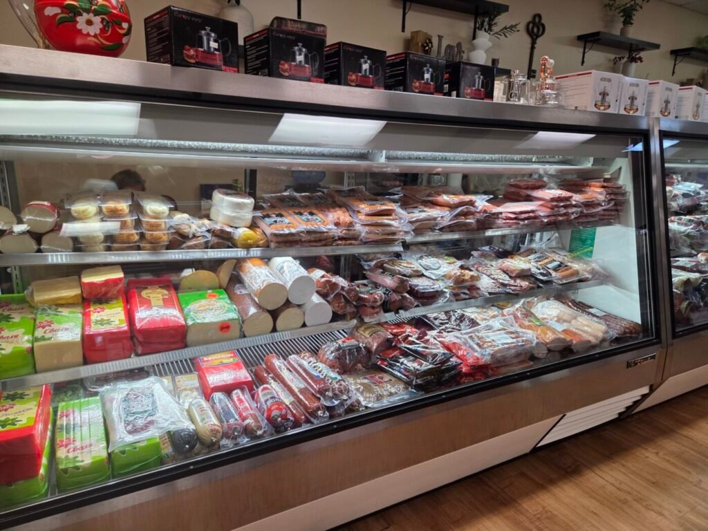 A refrigerated deli case at Golden Key filled with imported cheeses, smoked sausages, cured meats and Eastern European specialty foods.