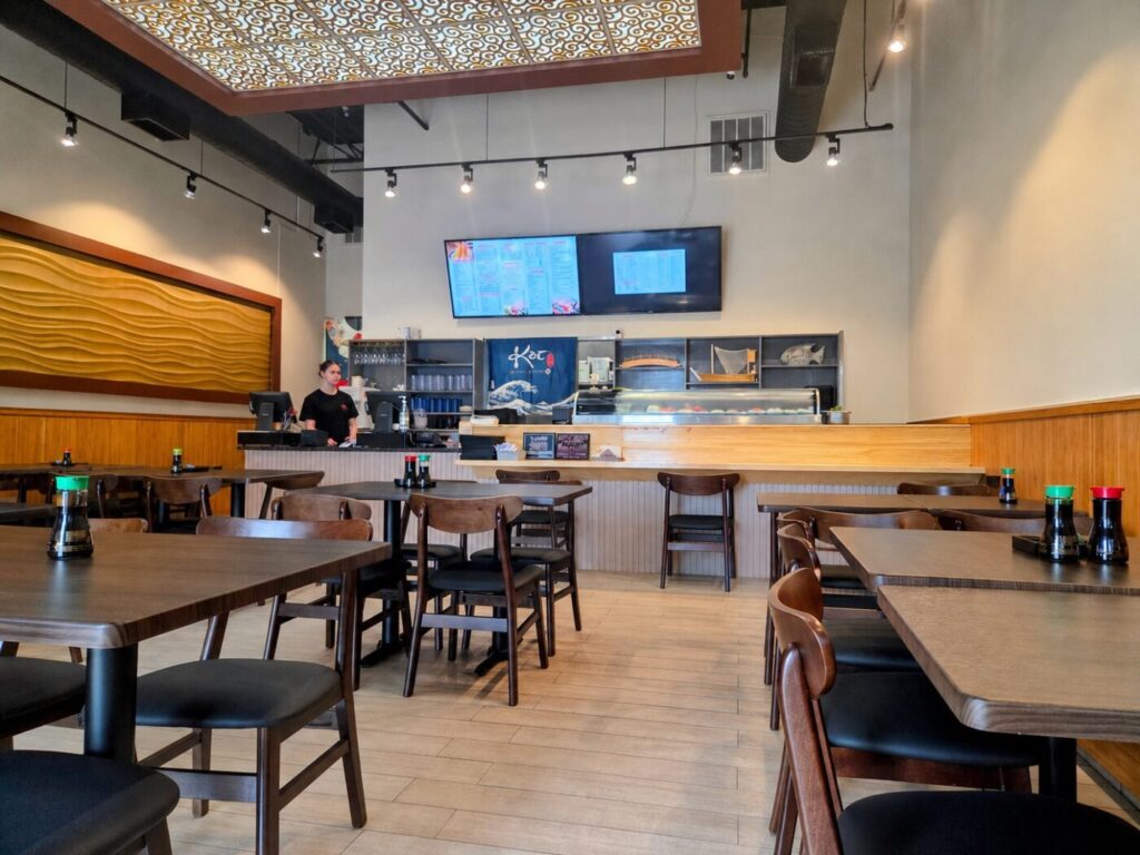 The dining room at Koi Sushi & Hibachi keeps a relaxed neighborhood feel, with an open sushi counter, warm wood trim and family-friendly seating.