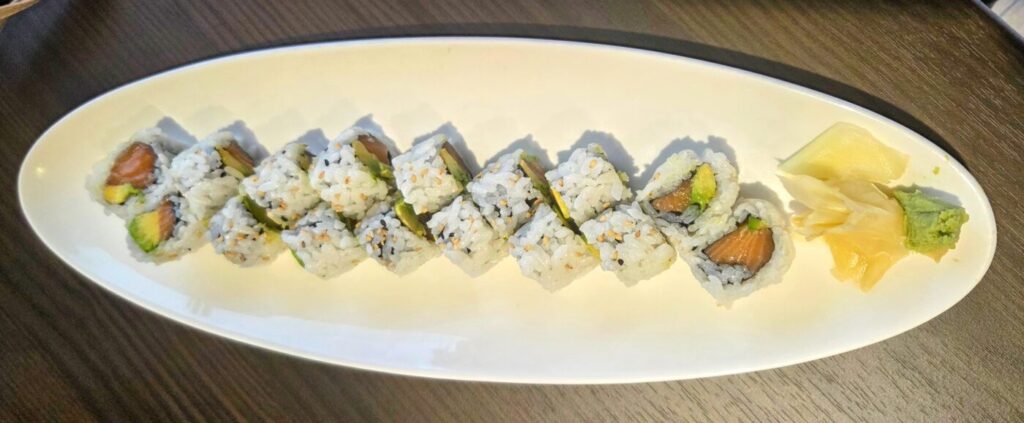 A simple salmon avocado roll served with pickled ginger and wasabi.
