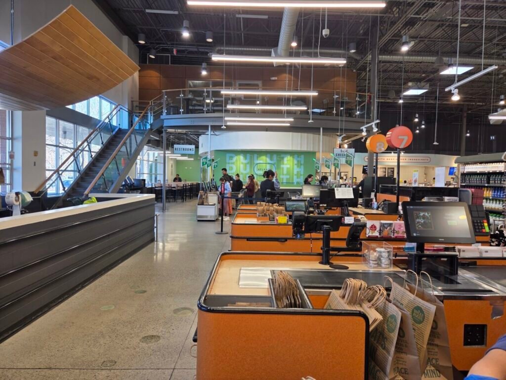 Interior of a Whole Foods store with checkout lanes, high ceilings and shoppers in the background