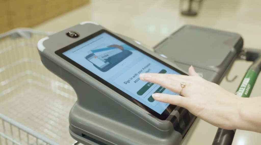 Shopper using a touchscreen to sign into a smart grocery cart before beginning a grocery trip.