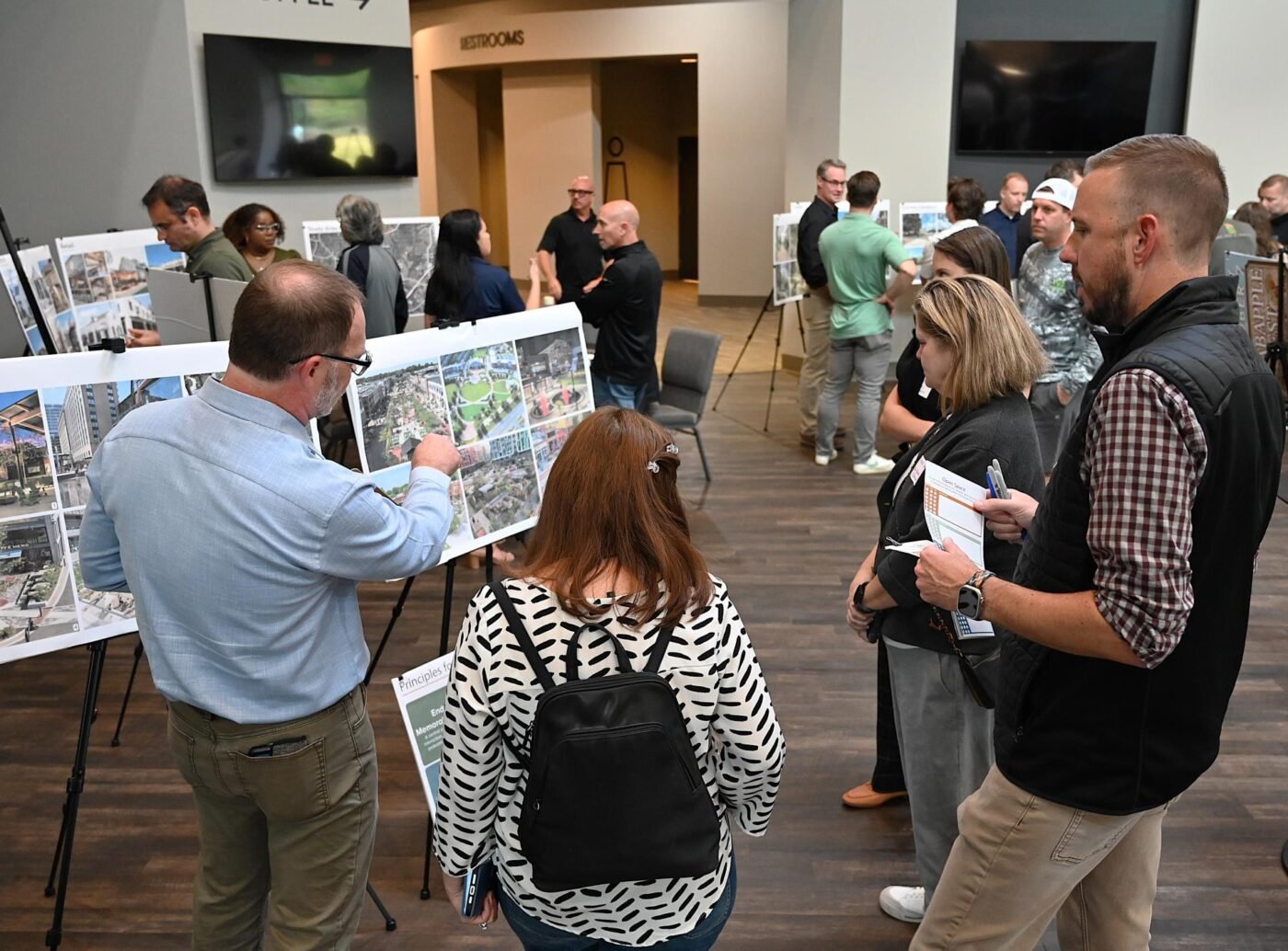 Residents review redevelopment materials during a Deerfield planning meeting. People review large display boards during an indoor public meeting about redevelopment plans.