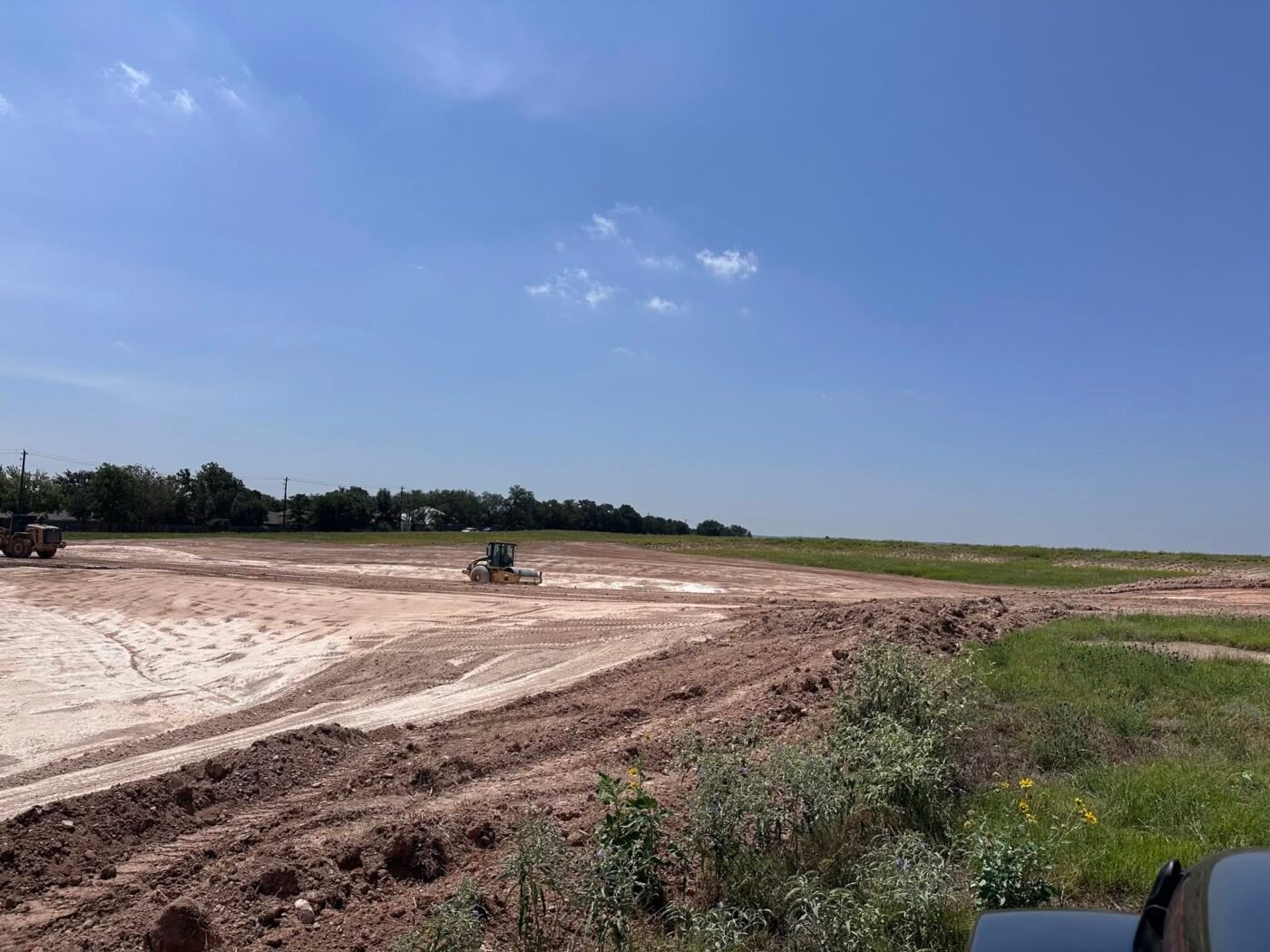 Construction site with graded dirt, heavy equipment and a wide open sky