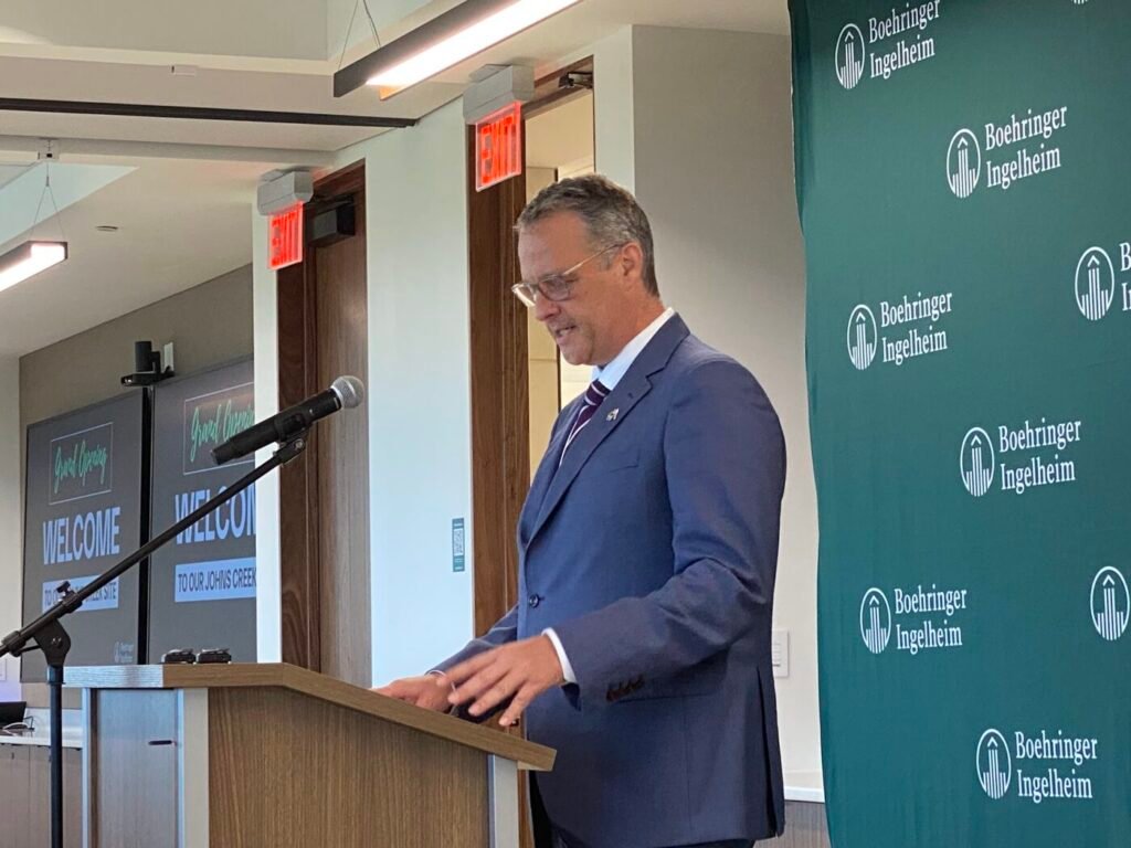Peter Ploeger in a blue suit speaks at a podium beside a Boehringer Ingelheim backdrop