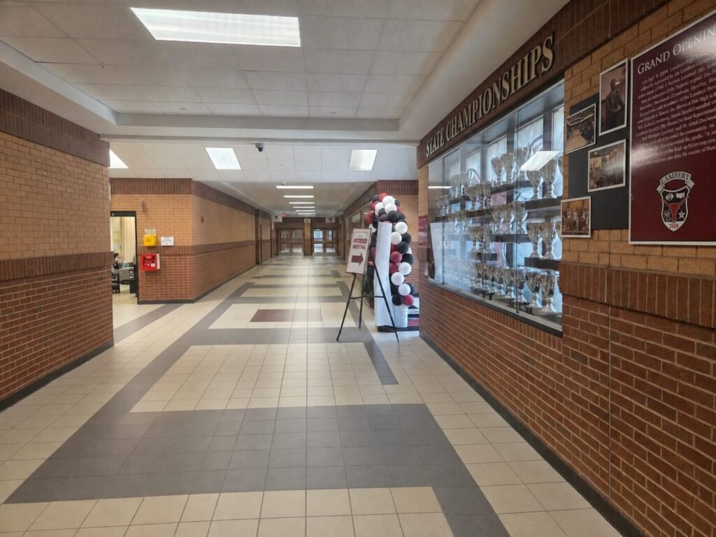 An empty hallway at Lambert High School with display cases and school signage.