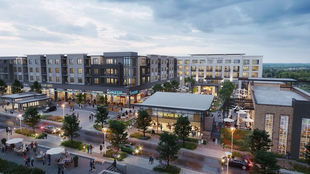 Dusk view of a busy mixed-use development with restaurants, apartments, sidewalks, cars and outdoor seating