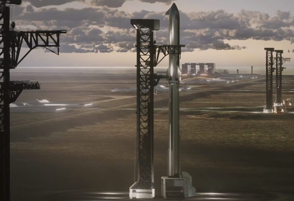 A rocket stands on a launch tower near the coast with additional infrastructure in the background
