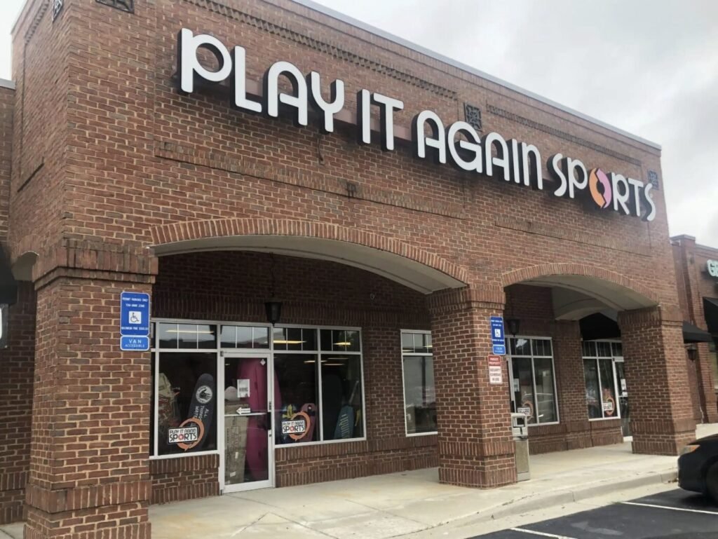 Brick storefront with a large Play It Again Sports sign above the entrance and display windows along the front.
