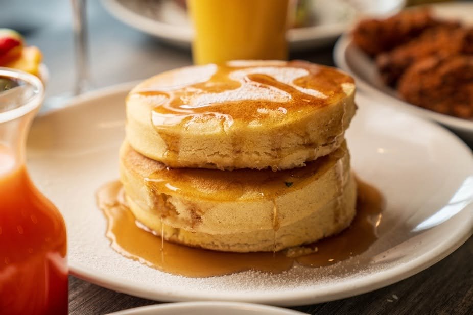 Two pancakes topped with syrup on a white plate