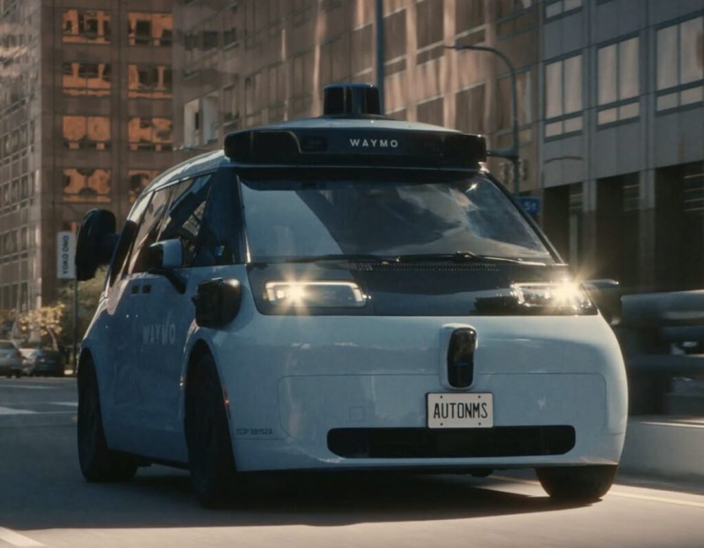 Front view of a Waymo minivan driving in a city street.