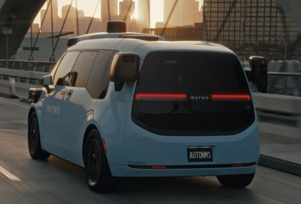 Rear view of a Waymo vehicle driving across a bridge at sunset.