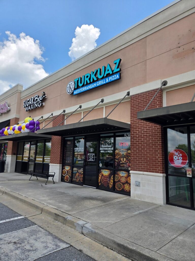 Strip-mall storefront with Turkuaz Mediterranean Grill & Pizza sign under a blue sky