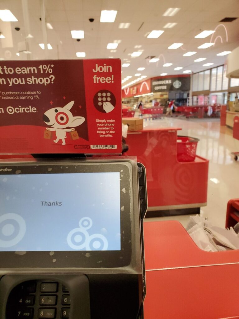 A Target checkout screen and self-service area with store seating in the background