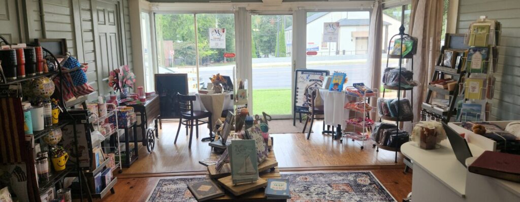 Bookstore interior with tables, shelves and a front window seating area