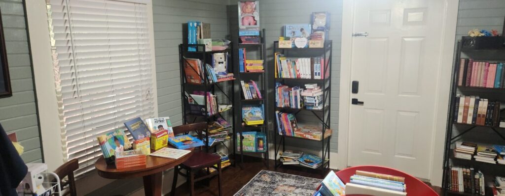 Children's books displayed on shelves and a small table beside a closed door