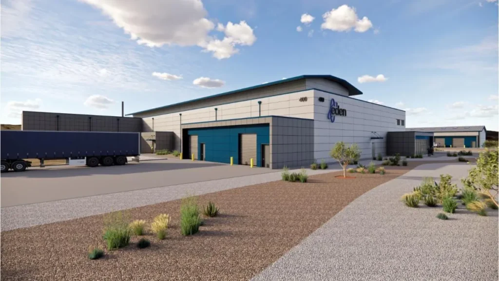 A large industrial building with the Eden logo, a truck trailer parked beside it, and a landscaped lot under a partly cloudy sky.