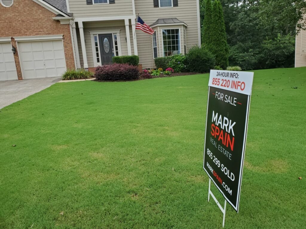 A for-sale sign on a lawn in front of a suburban house