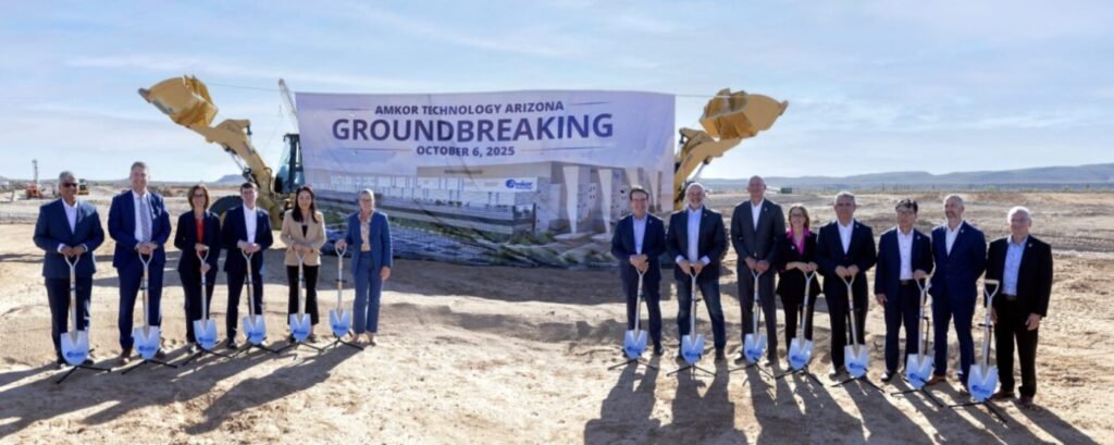 A group of people stand with shovels in front of a banner reading Amkor Technology Arizona Groundbreaking, October 6, 2025.