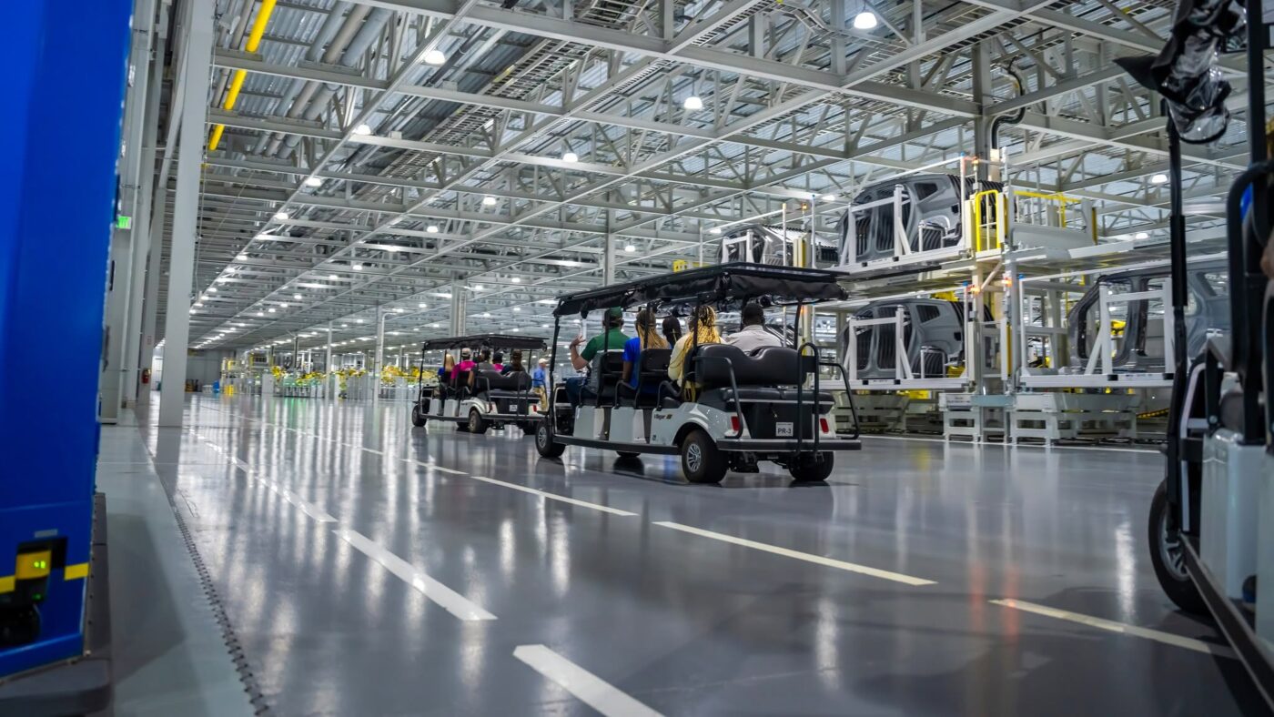 Empleados recorren en carros un amplio pasillo de la fábrica en Hyundai Motor Group Metaplant America.