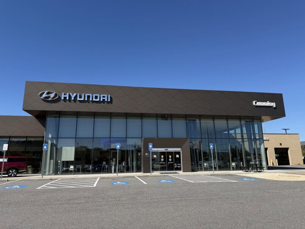 Concesionario Hyundai con fachada de vidrio, línea de techo oscura y cielo azul arriba