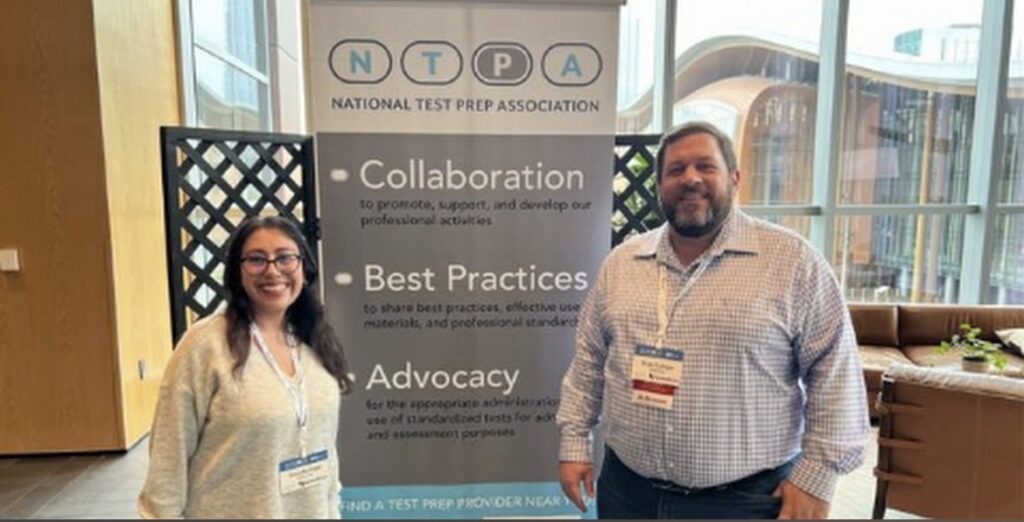 Man and woman standing in front of a National Test Prep Association banner.