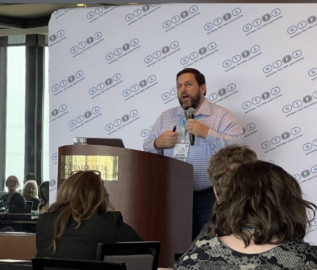 Man speaking at a podium in front of a National Test Prep Association backdrop.