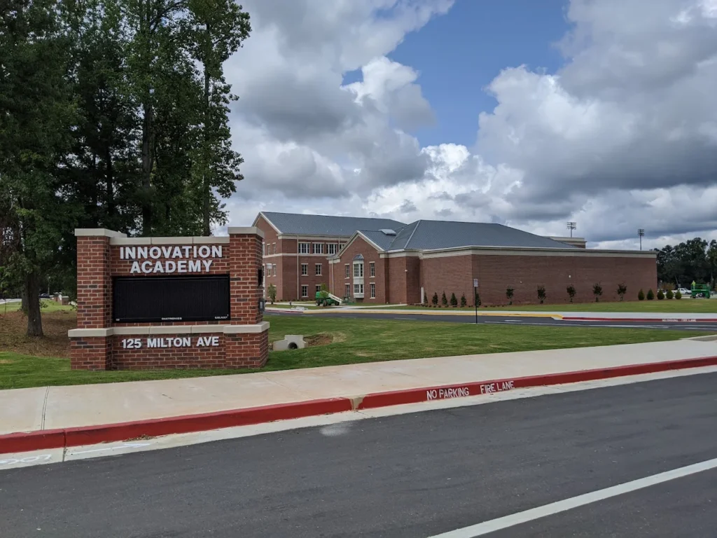 Innovation Academy sign in front of a brick school building under cloudy skies.