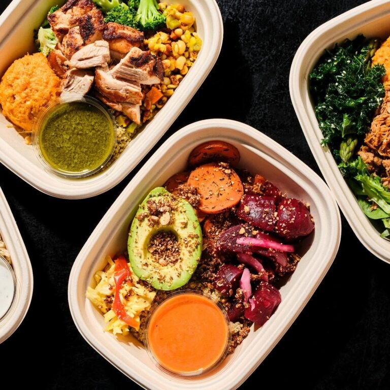 Three takeout bowls of customized food with vegetables, grains and protein on a black surface