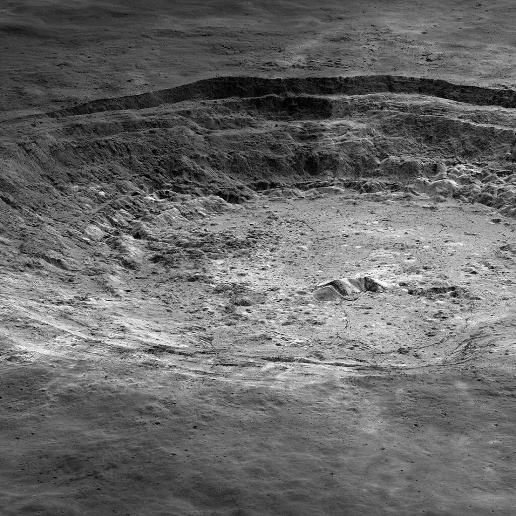 Close view of a wide crater with steep, layered walls and a rough floor on the Moon.