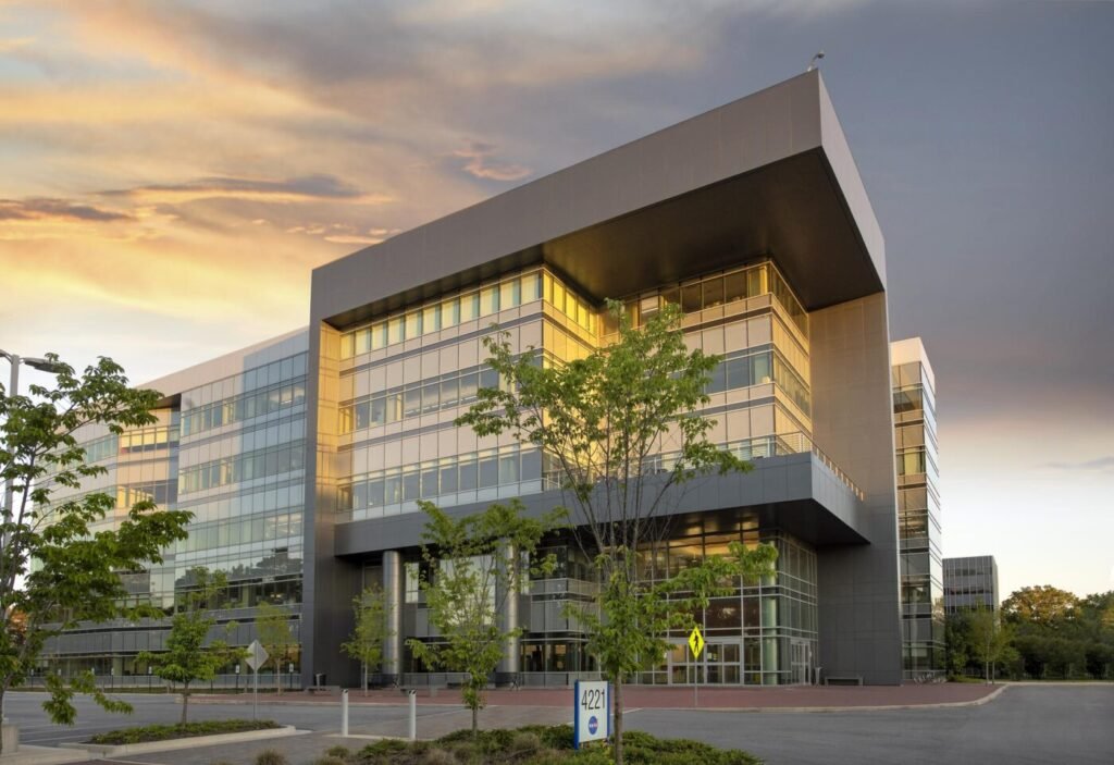 Modern glass-fronted NASA office building at sunset with trees in the foreground.