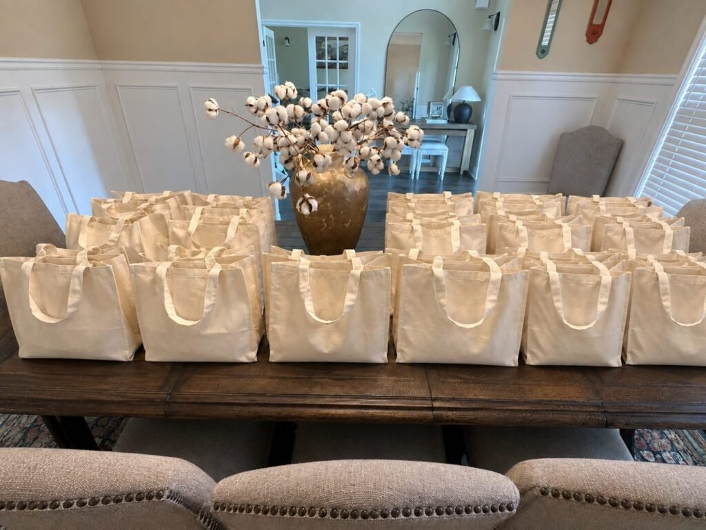 Rows of beige tote bags are arranged on a dining table in a home interior.