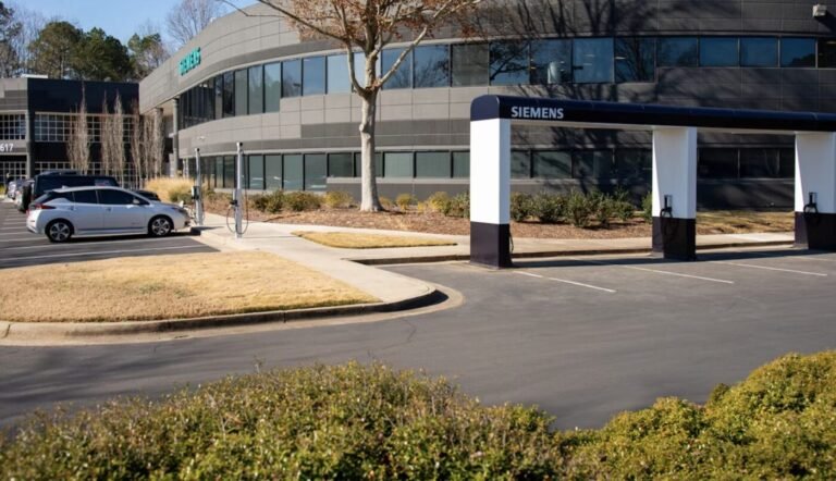Siemens signage stands near a curved office building and parking area on a sunny day.