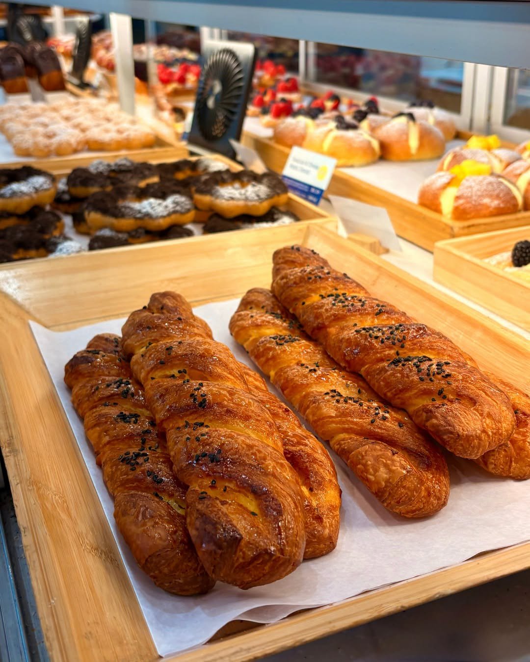 Tray of golden-brown pastries and breads in a bakery display case