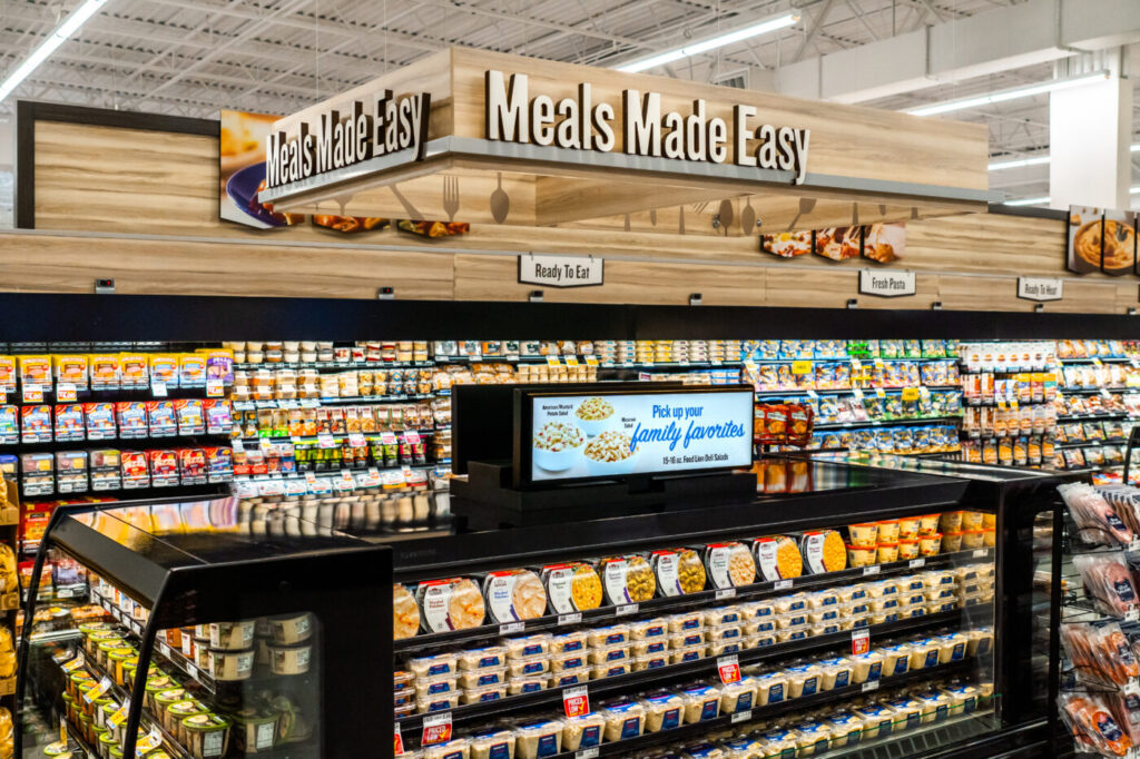 Prepared-meals section with refrigerated cases and overhead Meals Made Easy signage