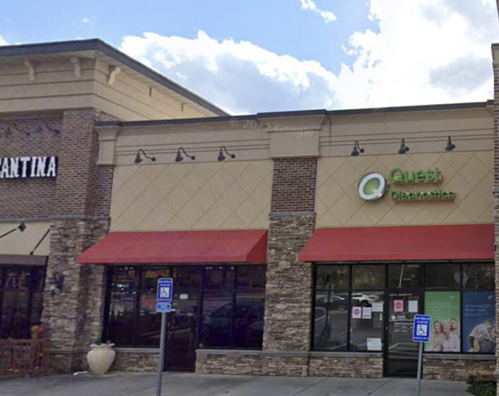 Quest Diagnostics storefront in a strip mall with red awnings and parking lot signs.