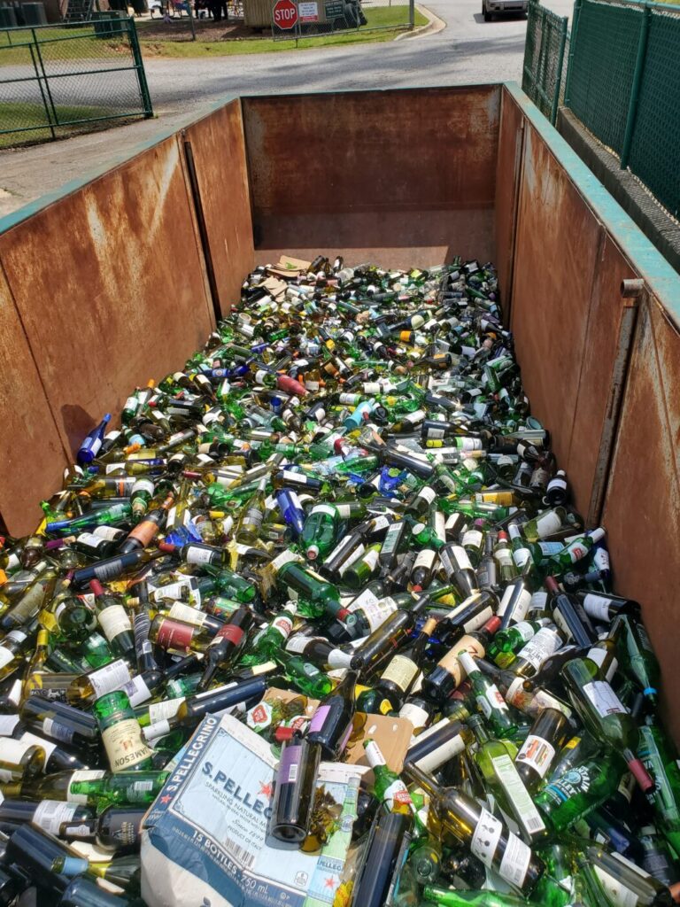 A large metal container filled with discarded glass bottles